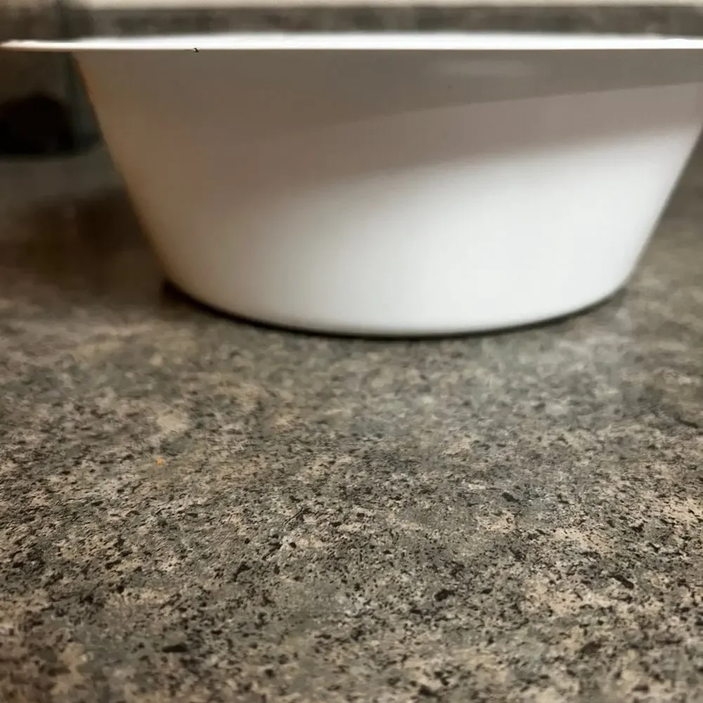 Enamel dog food or water bowl. Paw prints & bones adorn rim